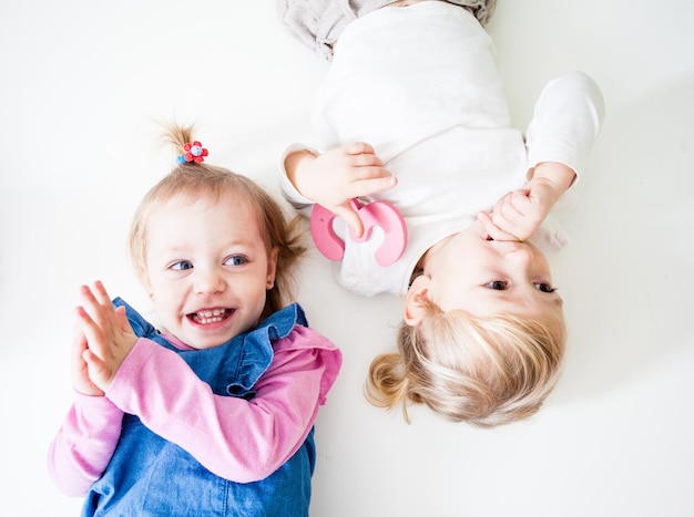 The little girls smiling and lying opposite one isolated