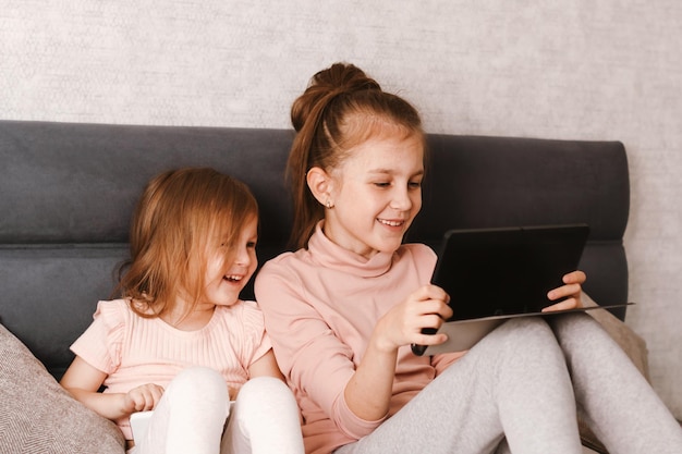 Little girls using laptop while sitting on sofa at home