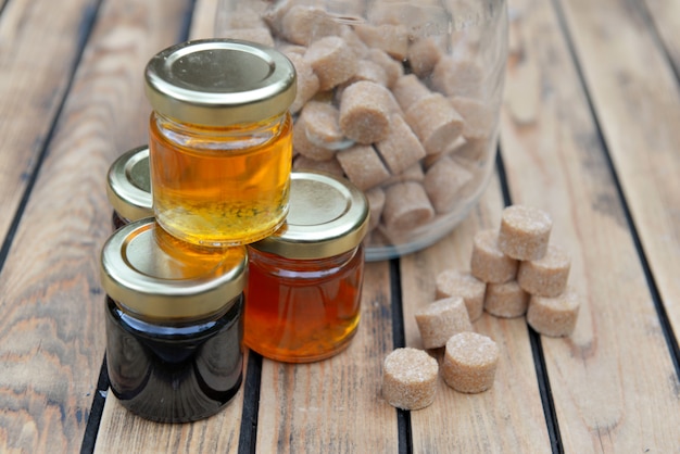 Little glass pots of various honey and brown sugar on a wooden table