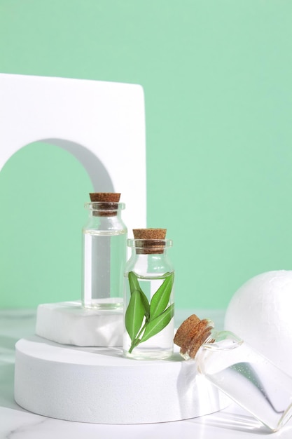 Маленький стеклянный флакон эфирного масла аромата в арке Сыворотка для лица в бутылке на зеленом столе