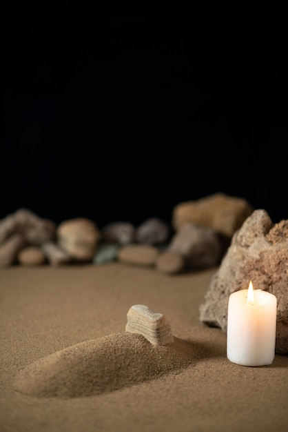 Little grave with candle and stones on sand funeral war death