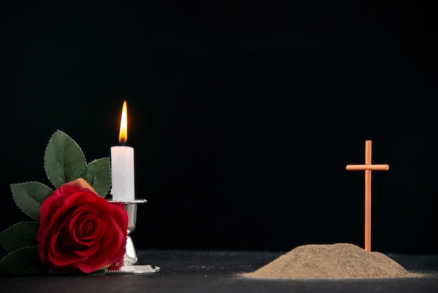 Little grave with candles and flowers as memory on a dark surface