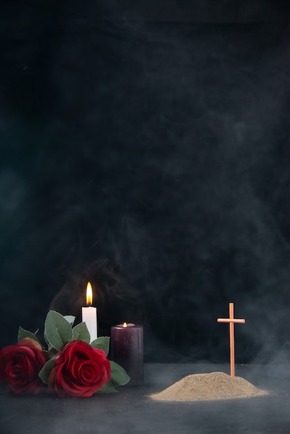 Photo little grave with candles and flowers as memory on dark surface