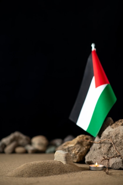 Piccola tomba con bandiera palestinese e pietre sulla superficie scura