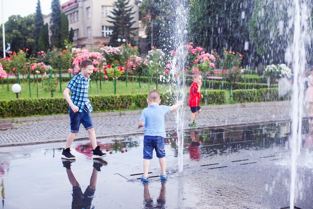 Little guys are playing with a stream of water in a city fountain