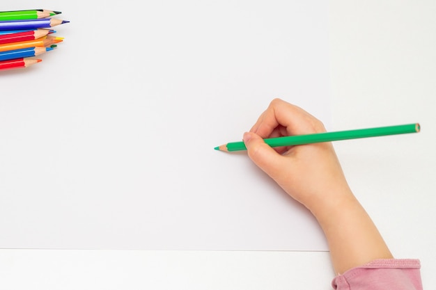 Little hand of girl drawing on paper.