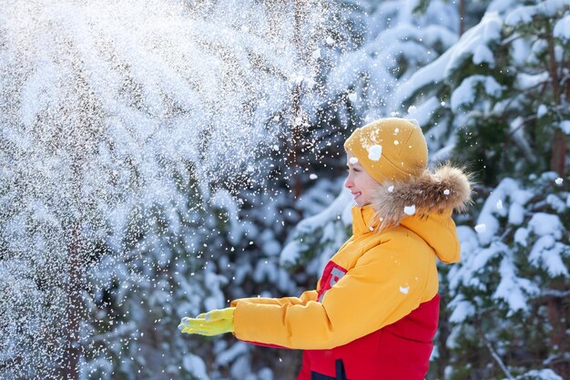 Little handsome boy is having fun outdoors in snowy winter park Child play outdoors in snow