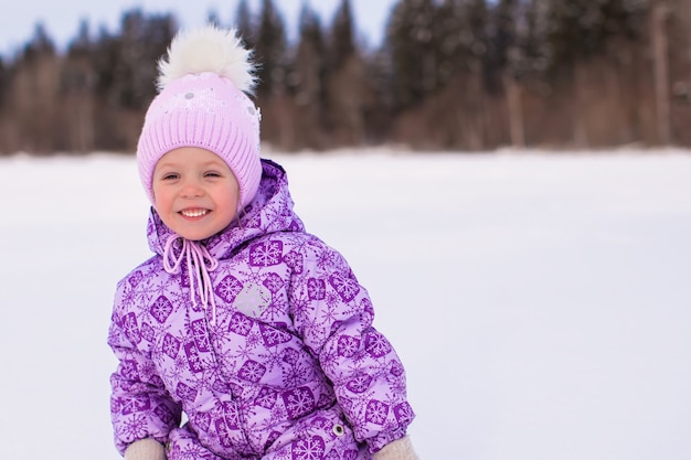 Little happy adorable girl having fun on the snow at winter sunny day