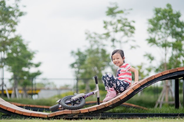 Little happy asian child girl ride bike at playground