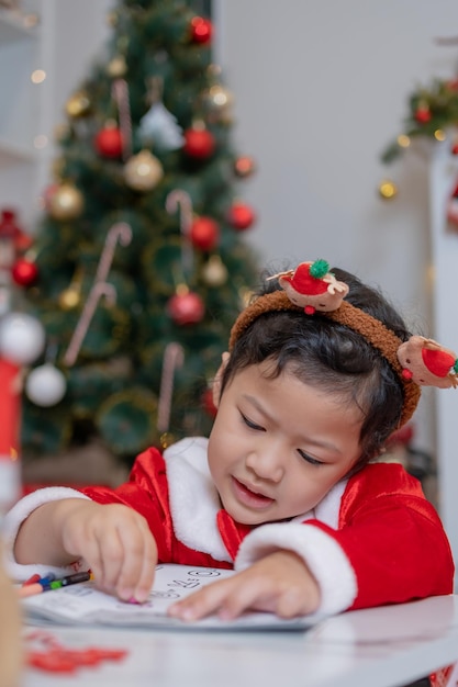 Little happy Asian girl have fun on Christmas party in the living room with decoration at home.