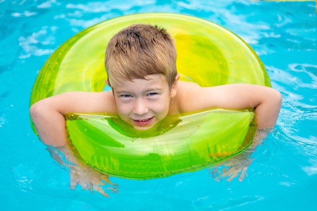 Little happy boy child swims in the pool on a rubber inflatable circle in summer summer childrens weekend childrens vacation kid in the water park