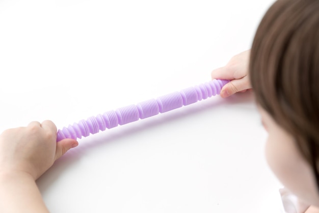 A little happy child girl plays with a pop tube fidget toy. Anti-stress sensory pop tube plastic toy in a kids hands.