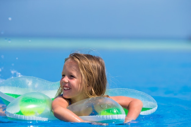 Little happy cute girl in outdoor swimming pool