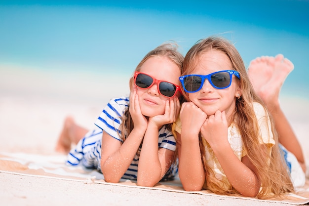 Little happy funny girls have a lot of fun at tropical beach playing together. Sunny day with rain in the sea