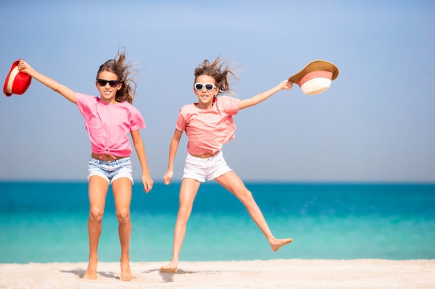 Little happy funny girls have a lot of fun at tropical beach playing together.