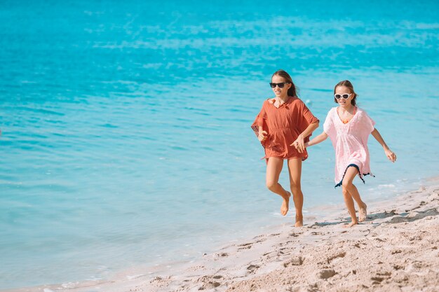 Little happy funny girls have a lot of fun at tropical beach playing together.