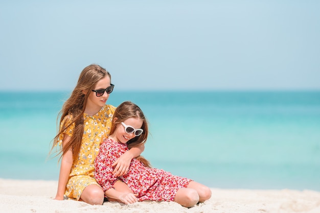 Little happy funny girls have a lot of fun at tropical beach playing together.