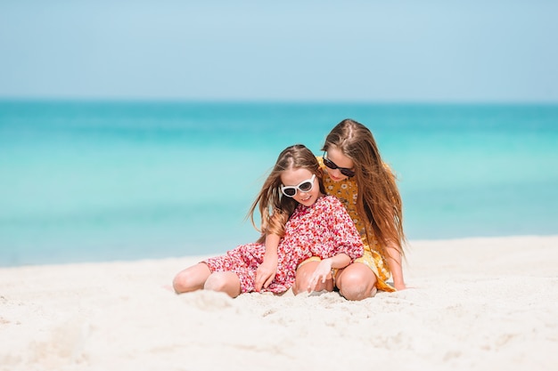 Little happy funny girls have a lot of fun at tropical beach playing together.