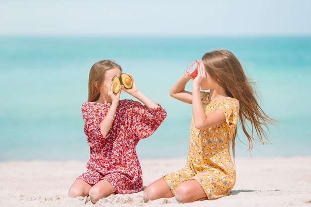 Little happy funny girls have a lot of fun at tropical beach playing together.