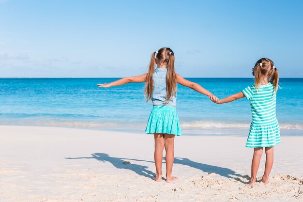 Маленькие веселые веселые девчонки веселятся на тропическом пляже, играя вместе