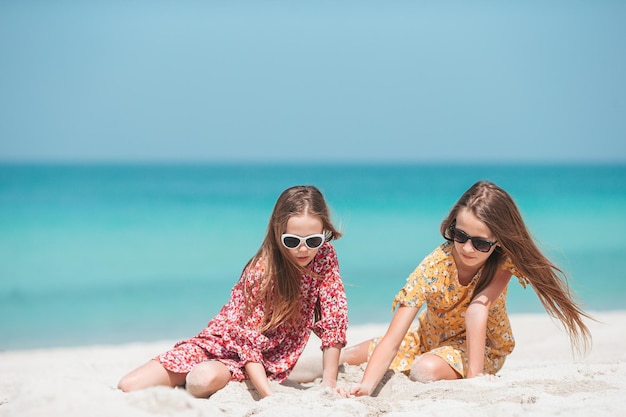 작고 행복한 재미있는 소녀들은 열대 해변에서 함께 노는 것을 많이 즐깁니다.