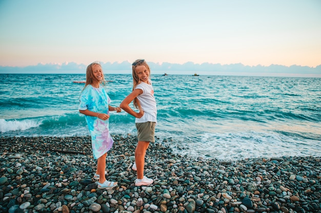 Photo little happy funny girls have a lot of fun at tropical beach posing together