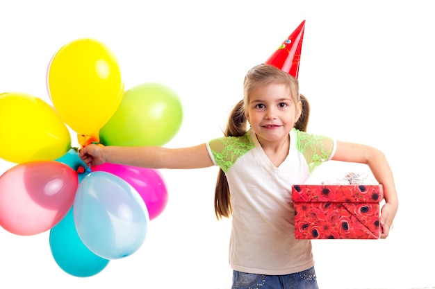 Little happy girl celebrating birthday with multicolor ballons with gift box in hands.