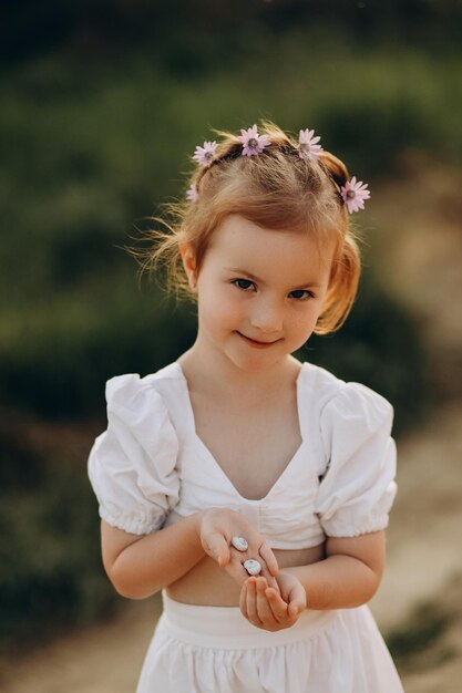 Foto bambina felice che si diverte nel parco estivo tiene i molluschi nelle sue mani