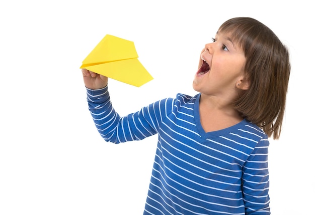 Маленькая счастливая девочка держит бумажный самолетик на белом фоне