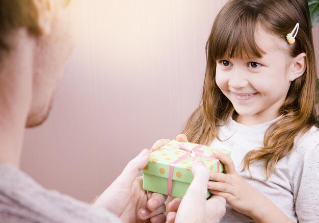 A little happy girl is holding a gift from her dad in her hands