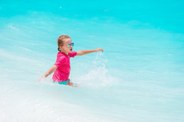 Little happy girl splashing in clear turquiose water