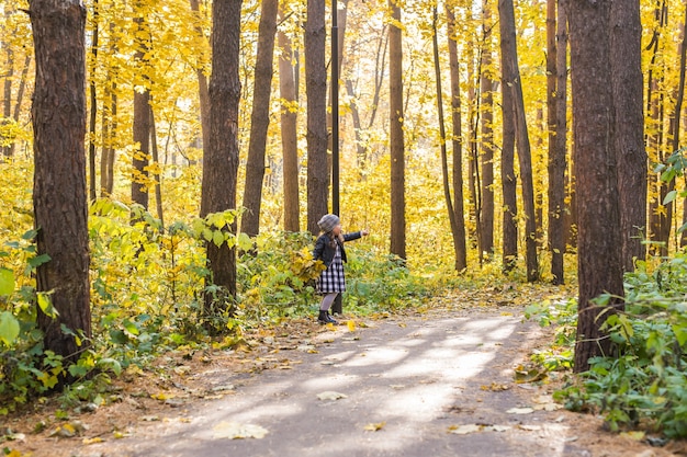 Piccola ragazza felice che cammina nella sosta di autunno