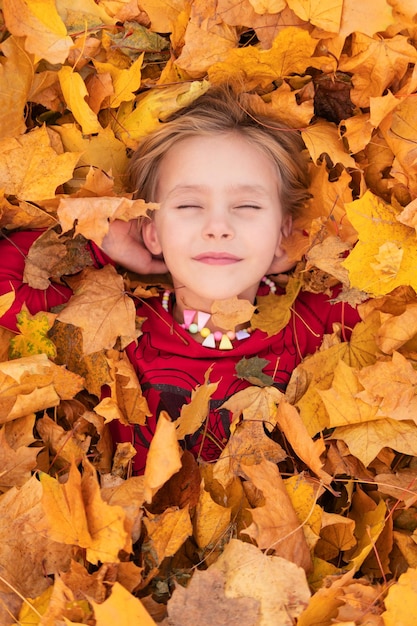 little happy girl with closed eyes in autumn foliage