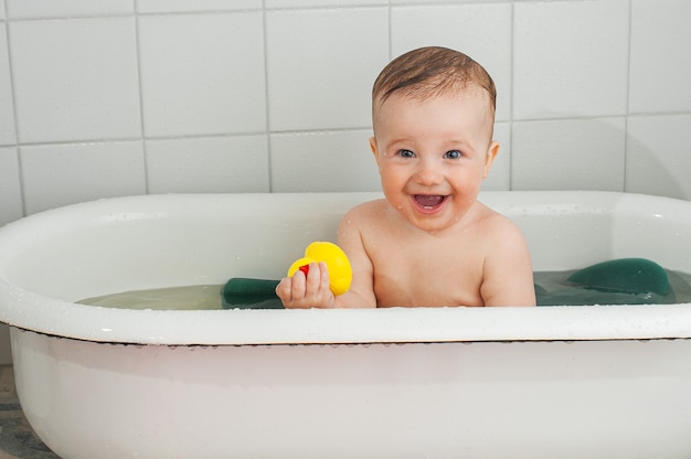 Little happy toddler bathes in a bathtub