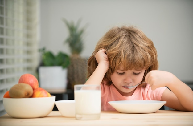 Little healthy hungry baby boy eating soup from with spoon