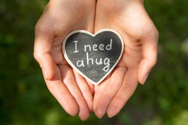 Photo little heart with i need a hug phrase in a hands sharing a hug concept