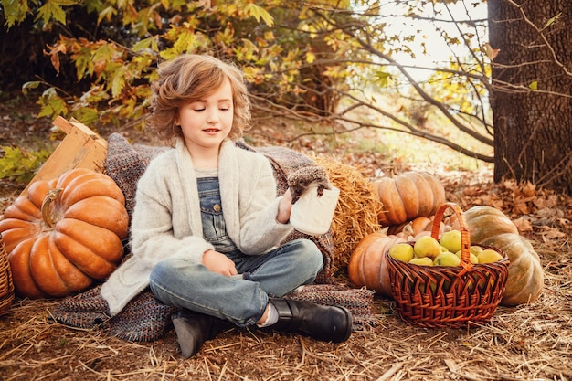 Little hedgehog in the hands of a cute girl Portrait of kid with pet Beige background Autumn background pumpkins haystack and red leaves harvest season