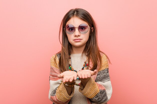 Little hippie girl holding something with palms, offering to camera.