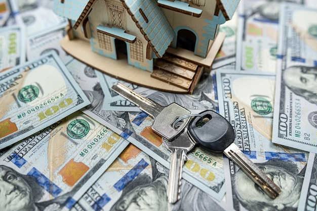 Little house model with many dollar banknotes and keys