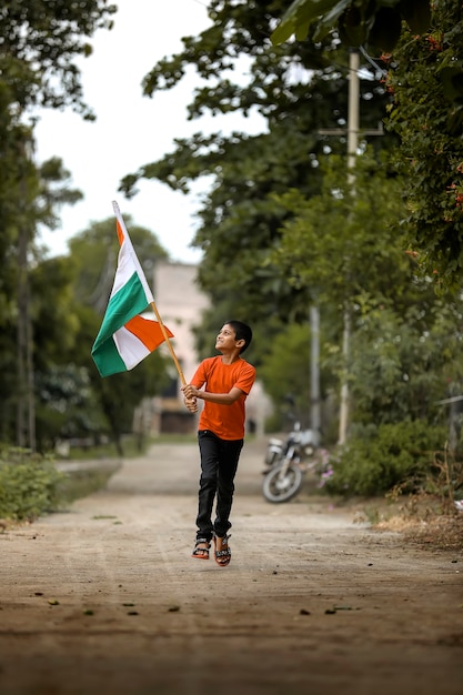 Little indian child holding, waving or running with Tricolour flag