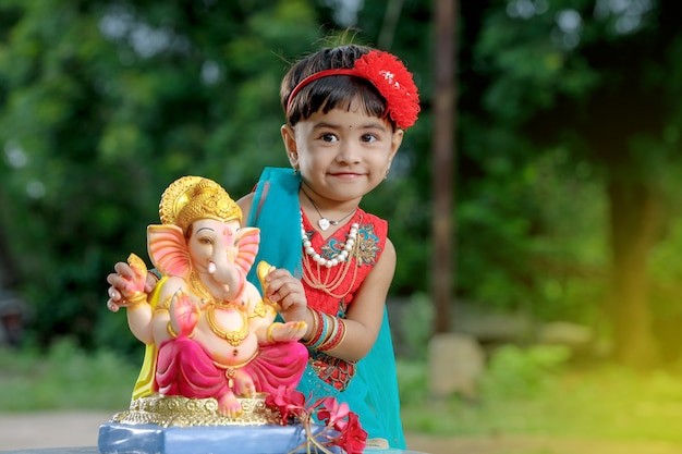 Little Indian girl child with lord ganesha and praying