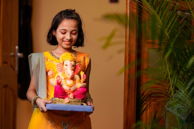 Little indian Girl with lord ganesha sclupture.