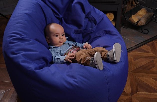 Маленький мальчик сидит на синем мешке с фасолью