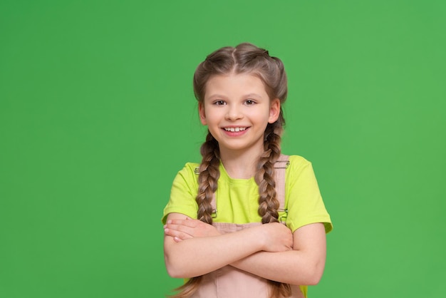A little joyful girl on a green isolated background.