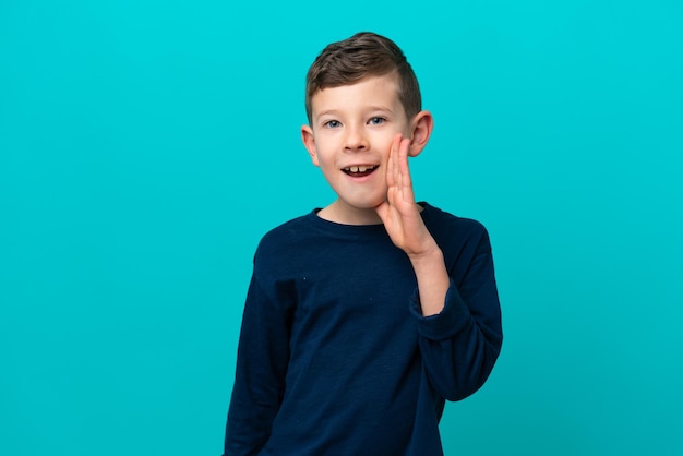 Little kid boy isolated on blue background shouting with mouth wide open