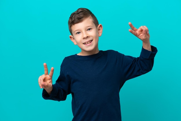 Little kid boy isolated on blue background showing victory sign with both hands