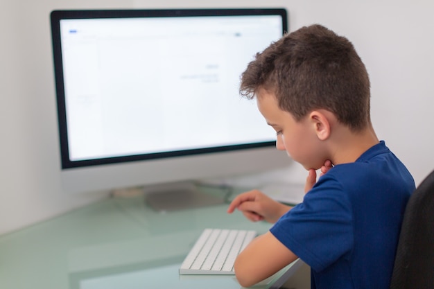 Little kid boy making school homework on computer notebook. Happy healthy child searching