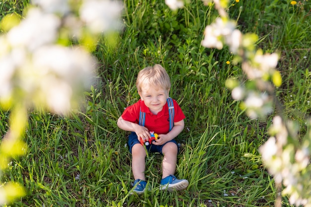 Little kid boy playing on grass colored toy