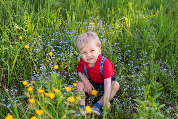 Little kid boy playing on grass colored toy