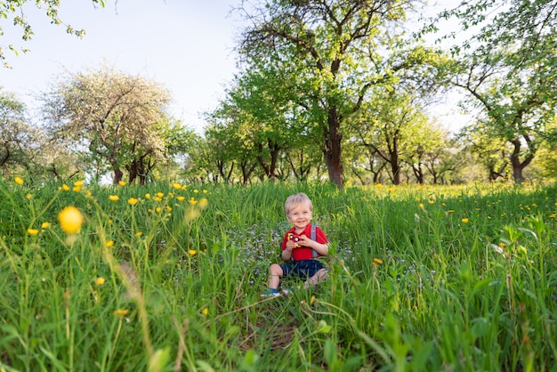 Little kid boy playing on grass colored toy